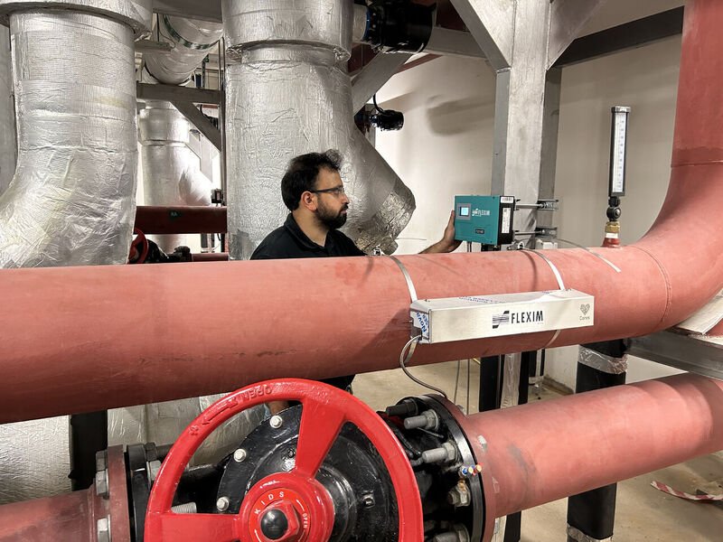 Technicien utilisant un débitmètre clamp-on portable Flexim non intrusif sur une canalisation lors d’une opération de maintenance.