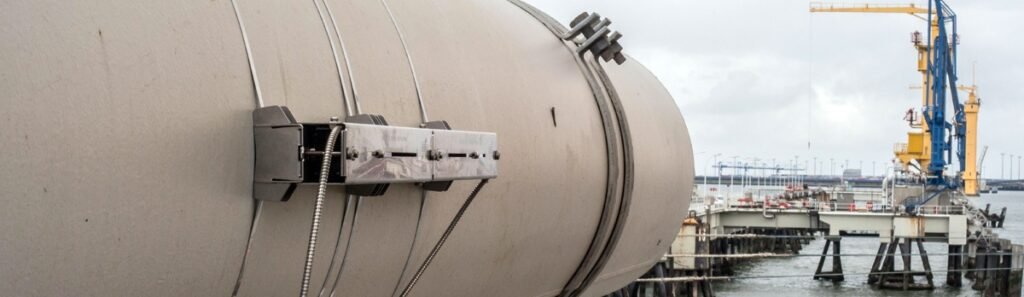 Débitmètre ultrason non intrusif de type clamp-on monté sur un pipeline de grand diamètre en environnement portuaire. Solution de mesure de débit non intrusive idéale pour le pétrole et le gaz, sans arrêt d’exploitation ni modification de la conduite.