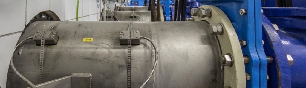 Débitmètre ultrason non intrusif de type clamp on installé sur une conduite de station de pompage permettant une mesure de débit non intrusif sans perçage ni interruption du process hydraulique industriel.
